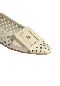 Beige Ballerinas aus perforiertem Leder, mit einer auffälligen goldenen Schnalle und einem schmalen Zehendesign. Flache Gummisohle sichtbar.