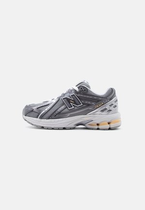 Gray and white New Balance 1906R running shoe with black logo, mesh upper, white laces, and cushioned sole with beige accents, side view.