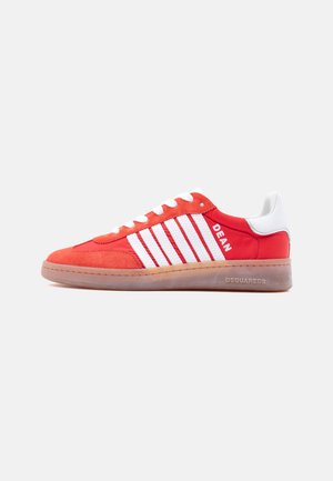 Rode en witte lage sneaker met witte strepen, veters aan de voorkant, gumzool en de merknamen "DEAN" en "DSQUARED2" aan de zijkant.