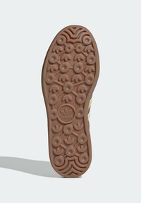 Shoe sole with circular and leaf-shaped tread patterns, featuring the Adidas trefoil logo in the center, in brown rubber material.