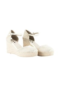 Wedges de espadrille trenzados en blanco con tiras al tobillo, parte superior de tela texturizada y tacones envueltos en yute, con un diseño de punta redondeada.