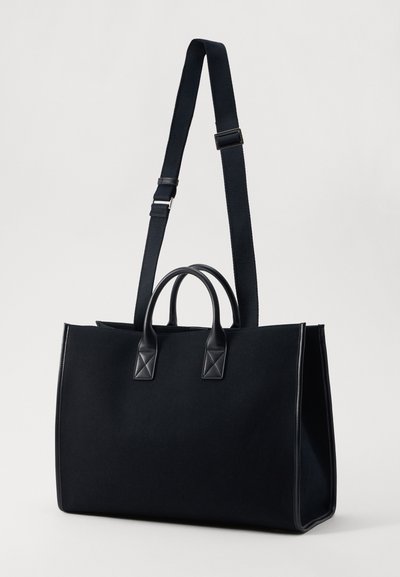 Borsa a tote nera in canvas con dettagli in pelle. Presenta due manici superiori e una tracolla regolabile. Design semplice e rettangolare.