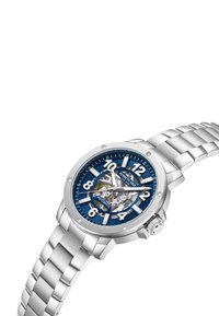 Srebrny automatyczny zegarek z niebieską tarczą, wyraźnymi znacznikami godzin, przejrzystym deklem oraz stalową bransoletą o plecionym wzorze.