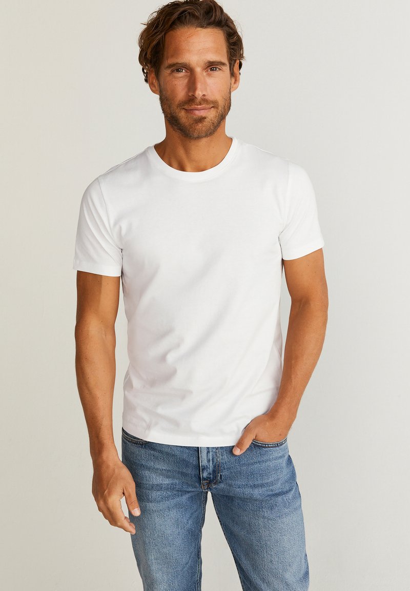 Hvid bomulds T-shirt med rund halsudskæring og korte ærmer, parret med blå jeans. Simpelt design, glat tekstur og klassisk pasform.