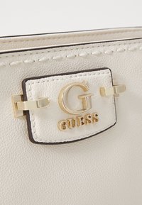 Borsa a tracolla in pelle bianca testurizzata con logo del marchio e accessori in tono oro, caratterizzata da cuciture dettagliate lungo i bordi.