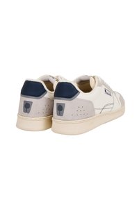 Sneaker bianchi e grigi con un accento blu navy. Presentano materiali in suede e pelle, perforazioni sui lati e un patch logo sul tallone.
