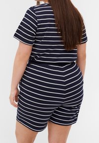 Pruhovaný bavlněný overal v námořnické modři a bílé barvě s krátkými rukávy, elastickým pasem a kraťasy. Má kulatý výstřih a pohodlný volný střih.