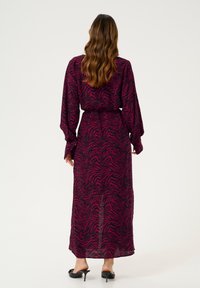 Purple long dress with black zebra print, long sleeves, a belt at the waist, and a flowing texture; worn with black heeled mules.