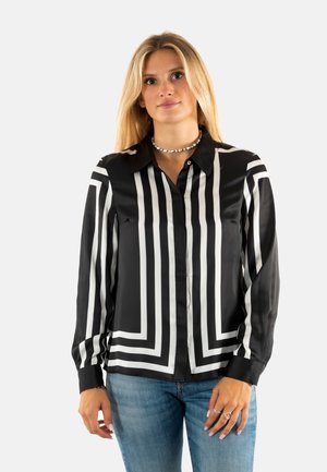 Blusa de manga larga a rayas blancas y negras con cuello, hecha de tela de satén, que presenta un cierre con botones y un diseño ajustado.