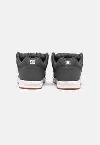 Gray sneakers featuring a smooth synthetic upper, padded collar, and white rubber sole with branding detail on the back.