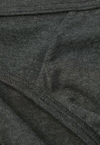 Kohlegrauer Stoff mit einer weichen Stricktextur, der Nähte und Falten aufweist. Das Material wirkt leicht und dehnbar.