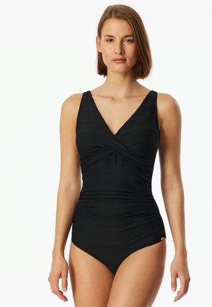 Black one-piece swimsuit with V-neckline and crossover design. Made of textured material with gathered sides, featuring a gold accent detail.
