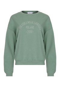 Felpa verde con collo a giro e polsini a coste. Presenta un testo in rilievo che recita "LE RAGAZZE FORTI INDOSSANO LAURELLA POLONIA 2018."