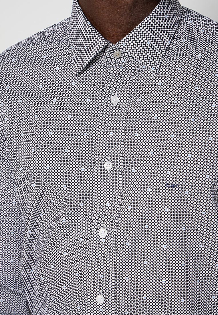 Camisa de manga corta con un patrón circular en blanco y negro, cuello abotonado y botones blancos lisos. Pequeño logotipo bordado en el pecho.
