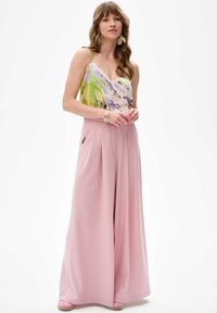 Mouwloos, meerkleurig top met een bloemmotief en kantafwerking, gecombineerd met hoge taille, geplooide, pastelroze wijde broek.