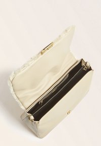 Beige læderhåndtaske med en tekstureret finish, der har pelskant, guldfarvede metaldele og en inderlomme med lynlås til organisering.