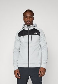 Grey zip-up hooded sweatshirt with black accents and logo. Features drawstrings, a smooth texture, and side pockets.