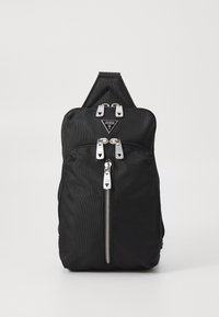 Zwarte stoffen rugzak met een slank ontwerp, zilverkleurige hardware, dubbele ritsen en een driehoekige logopatch op de voorkant.