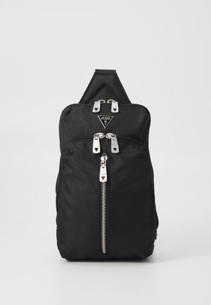 La mochila de tela negra presenta un diseño elegante, hardware plateado, dobles cremalleras y un parche de logo triangular en el frente.