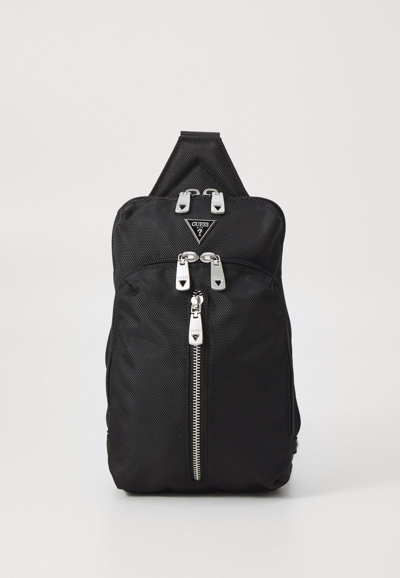 La mochila de tela negra presenta un diseño elegante, hardware plateado, dobles cremalleras y un parche de logo triangular en el frente.