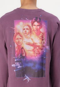 Purple cotton long-sleeve shirt featuring a multicolored graphic print of four characters and spaceships against a nebula background.