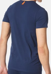 Marineblå kortærmet t-shirt fremstillet af glat bomuld, med rund halsudskæring og et orange mærke på ryggen.