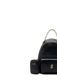 Mochila de cuero negro con una forma redonda estructurada, asa de cadena dorada, bolsillo frontal y un pequeño estuche con la marca adjunto.