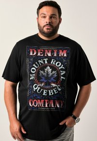 T-shirt en coton noir avec un grand graphique multicolore portant la mention "Denim Mount Royal Quebec Company" et un design de feuille d'érable stylisée.