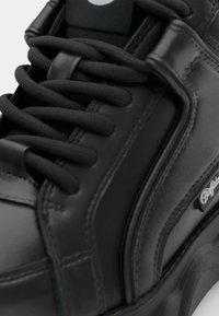 Svarta lädersneakers med rund tå, texturerad yta, tjocka snören, vadderad krage och sidodetalj med logotyp. Slät och glansig finish.