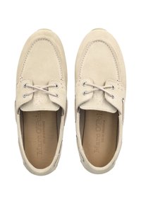 Beige Wildleder-Bootsschuhe mit abgerundetem Zehenbereich, zwei Ösen und Schnürdesign. Das Innere verfügt über ein geprägtes Markenlogo auf der Lederinnensohle.