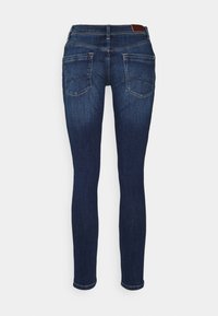 Jeans skinny in denim blu scuro, con design a cinque tasche, passanti per la cintura e una leggera sfumatura sulle cosce, tessuto testurizzato con leggero elastico.