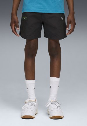 Shorts noirs en tissu léger, avec un design brodé. Associés à des chaussettes blanches et des chaussures de sport blanches avec des accents.