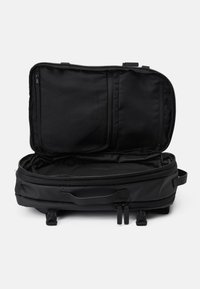 Bolsa de viaje negra con un zipper abierto. Fabricada con material duradero, cuenta con un interior espacioso con bolsillos y una base plana para mayor estabilidad.