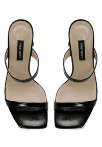 Black high-heeled sandals with a glossy finish, square toe, open design, and double ankle straps. Features a beige insole with logo.