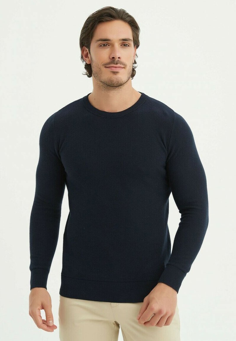 Pull en tricot bleu marine à manches longues et col rond. Il présente des poignets et un ourlet côtelés, ajoutant texture et structure.