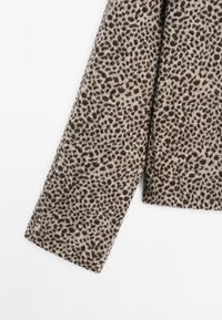 Leopard print jacket sleeve in beige and brown, featuring a soft texture and a straight cut with a clean finish on the edge.