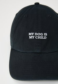 Cappellino da baseball nero in tessuto con visiera curvata. Presenta un testo ricamato bianco che dice "IL MIO CANE È IL MIO BAMBINO". Design semplice senza dettagli aggiuntivi.