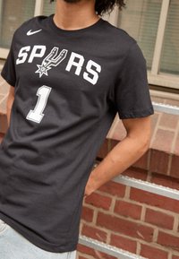 Schwarzes Baumwoll-T-Shirt mit weißem "SPURS"-Text und der Zahl "1" auf der Vorderseite. Kurzarm und Rundhalsausschnitt.