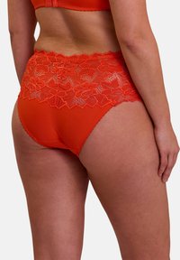 Braguita de encaje rojo de talle alto con patrones florales, suaves tejidos combinados y bordes festoneados, que presenta un acabado liso y una cinturilla elástica.