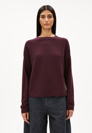 Bordeaux roter Pullover mit langen Ärmeln, rundem Halsausschnitt und Rippstruktur. Kombiniert mit locker sitzenden, dunkelgrauen Jeans. Einfaches und modernes Design.