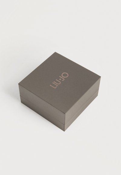 Затворена квадратна тъмносива кутия за бижута с надпис "LIU•JO" в светлорозово отгоре, поставена на обикновена светла повърхност.