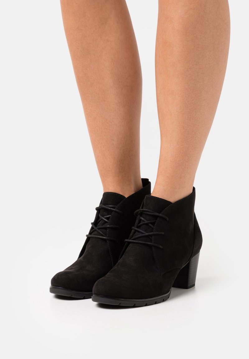 Black suede ankle boots with a rounded toe, lace-up closure, and a block heel. The texture is soft with a matte finish.