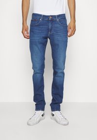 Jeans i denim med medelblå tvätt och smal passform. Har fem fickor, knappstängning och subtil blekning på låren.
