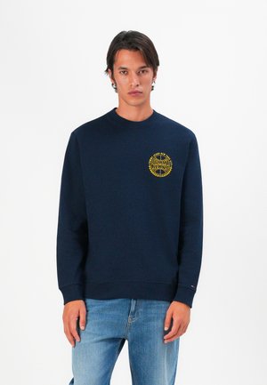 Marineblauwe sweatshirt met een ronde halslijn, ribgebreide manchetten en onderkant. Bevat een gele geborduurde logo op de linkerkant van de borst. Gemaakt van zacht materiaal.