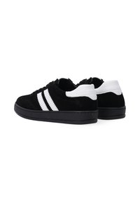 Czarne zamszowe sneakersy z trzema białymi paskami, zaokrąglony czubek, czarna gumowa podeszwa i białe akcenty na pięcie; niski fason.