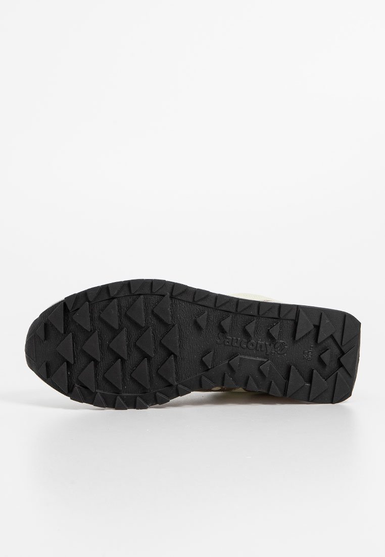 Suela de zapato de goma negra con profundos dibujos en forma de triángulo y el logotipo de "Saucony" grabado en el centro, mostrado sobre un fondo blanco.