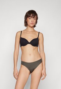 Soutien-gorge rembourré noir avec bretelles réglables, texture lisse. Bas de bikini vert olive, coupe taille basse, design sans coutures. Fond neutre.
