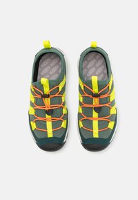 Grønne og grå sko med mesh-materiale, som har gule detaljer og oransje snøring. Skoene har en slip-on design og en teksturert såle for godt grep.