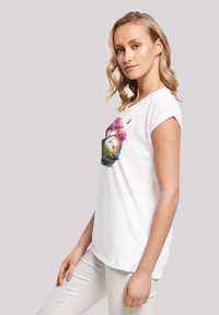 Weißes Baumwoll-T-Shirt mit einem bunten Baum- und Landschaftsdesign. Kurze Ärmel mit aufgerollten Säumen. Leicht abgerundeter Saum.