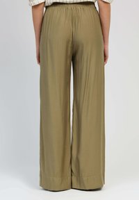 Pantalons à jambes larges en tissu vert olive. Ceinture élastique, texture lisse et coupe décontractée. L'ourlet présente un simple détail de revers.